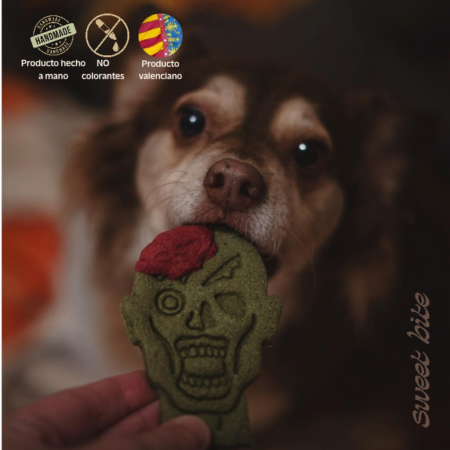 Perro disfrutando de nuestras galletas naturales de Halloween para perros con forma de cabeza de zombie. Destacan los sellos de elaboración artesanal valenciana y sin colorantes.
