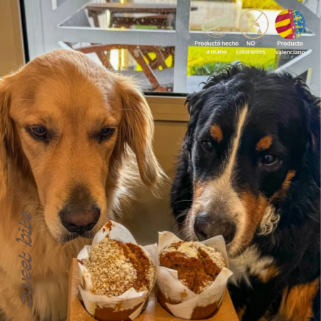 Dos perros mirando atentamente nuestros muffins halloween para perros, donde se muestran los sellos de producto hecho a mano, sin colorantes y de origen valenciano.
